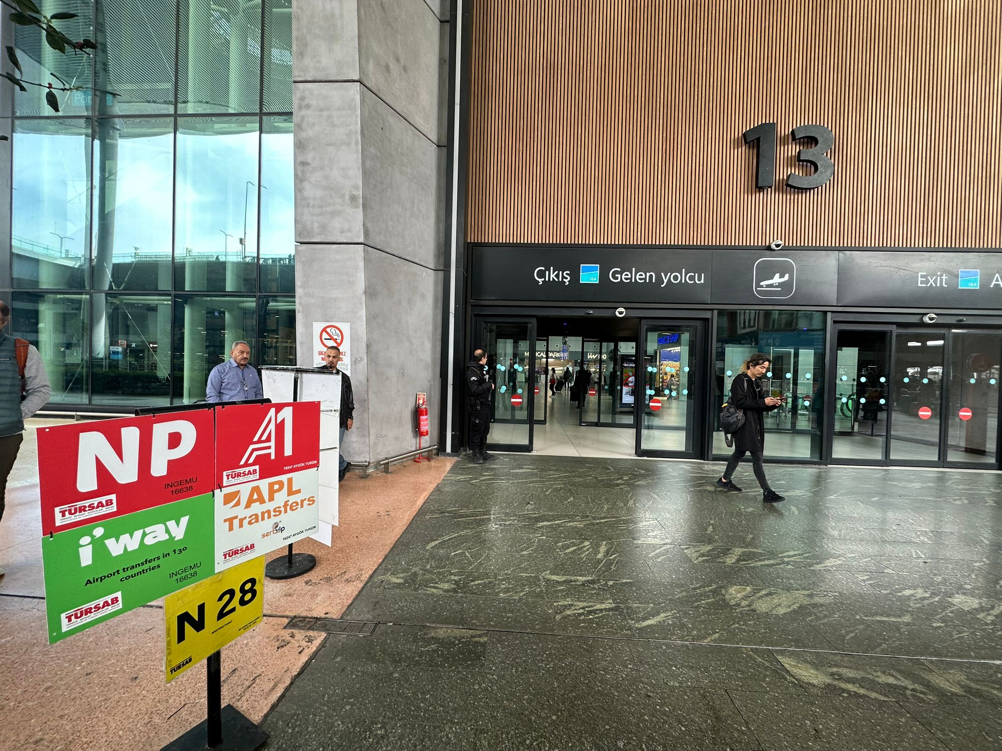 Exit Door 13 at Istanbul Airport with the APL Transfers sign
